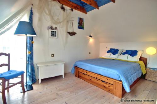 een slaapkamer met een bed met blauwe lakens en een stoel bij Roscoff Santec Maison Mer Bretagne in Santec