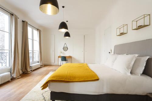 a bedroom with a large bed with a yellow blanket on it at Appartement Monceau in Paris