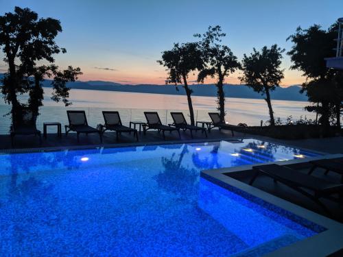 een zwembad met stoelen en uitzicht op het water bij Golden Sunset Apartments in Ohrid