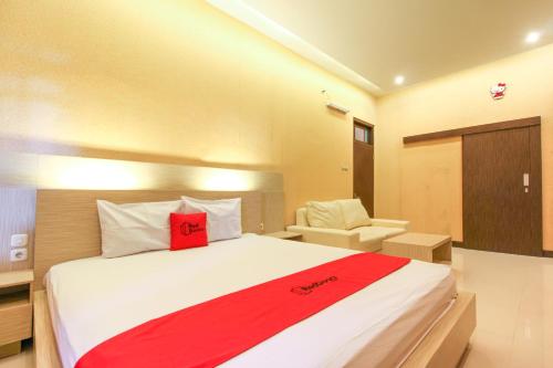 a bedroom with a large bed and a chair at RedDoorz near Candi Ratu Boko in Yogyakarta