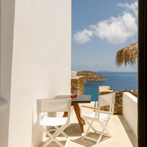 a table and chairs on a balcony with a view of the ocean at The Summit of Mykonos in Kalo Livadi