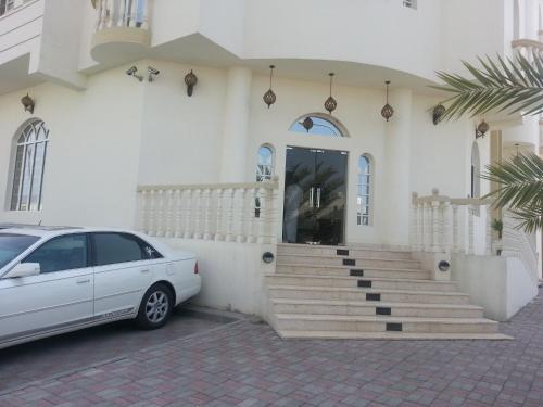 a white car parked in front of a building at Al Ferdous Hotel Apartments in Muscat