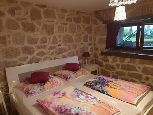 two beds in a room with a stone wall at Apartment Peky in Rab