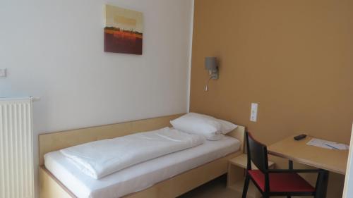 a bed in a room with a desk and a chair at Gästehaus Eisenstrasse in Trofaiach