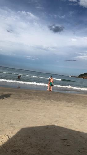 a group of people standing on a beach with a dog at 210 B Espelho das Aguas in Florianópolis