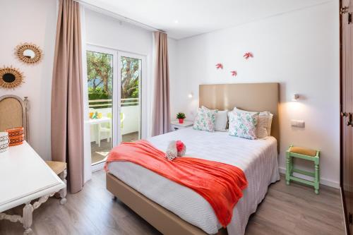 Apartamentos Flor da Laranja, Albufeira في ألبوفيرا: غرفة نوم بسرير وبطانية حمراء