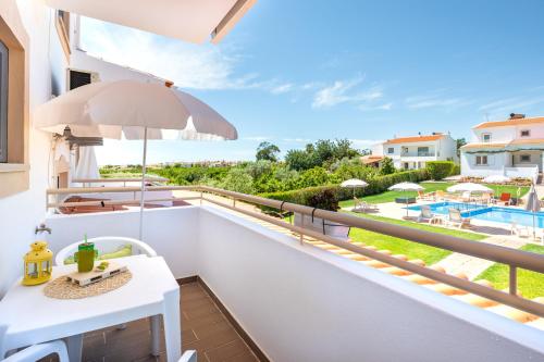 a balcony with an umbrella and a view of the ocean at Apartamentos Flor da Laranja, Albufeira by AlgarveBlossom in Albufeira