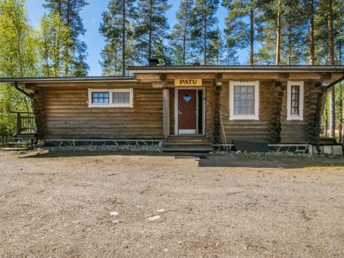 a log cabin with a red door in the woods at Holiday Home Patu by Interhome in Pihlajaniemi