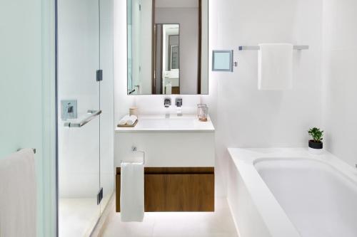 a white bath tub sitting next to a white sink at Vida Emirates Hills in Dubai
