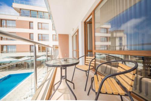 a balcony with a table and chairs and a pool at Balchik Sea View Apartments in Princess Residence in Balchik