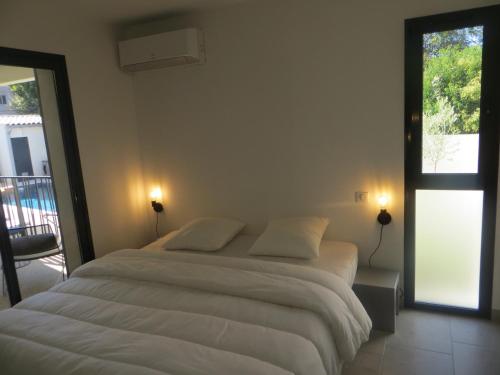 a bedroom with a large white bed with a balcony at Résidence "Les cyclistes", appartement "Akotee" in Malaucène