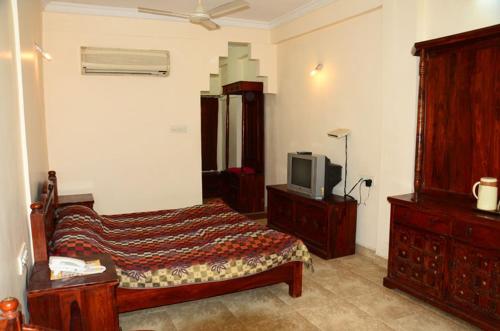a bedroom with a bed and a tv in it at Nakhrali Dhani Resort in Indore
