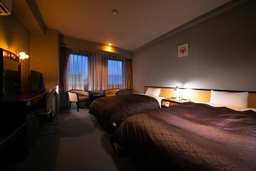 um quarto de hotel com duas camas e uma televisão em Hotel Satsukien em Kanoya
