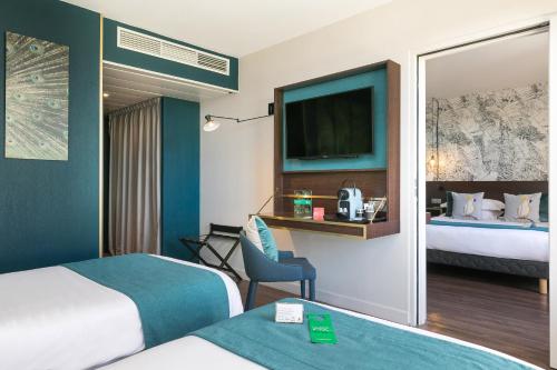 a hotel room with two beds and a television at Hôtel Birdy by Happyculture in Aix-en-Provence