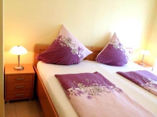 1 dormitorio con 2 camas con almohadas moradas en Comfort Apartments SNF zertifiziert, en Gronau