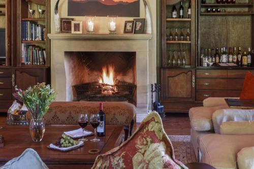 a living room with a fireplace and a table with wine glasses at Mount Camdeboo Private Game Reserve by NEWMARK in Graaff-Reinet