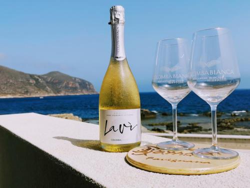 uma garrafa de vinho e dois copos numa mesa em Ajamola em Favignana