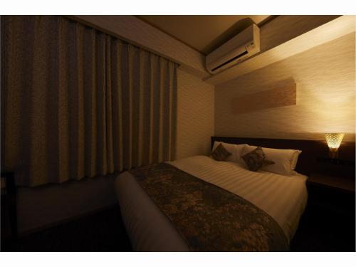 a bedroom with a bed and a window with a lamp at Rinn Miyagawacho Grande in Kyoto
