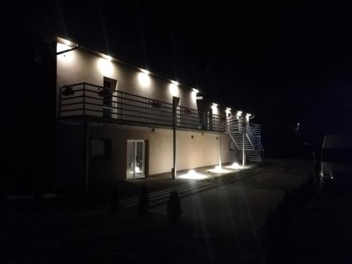 a building with lights on the side of it at night at Ararauna in Kamienica