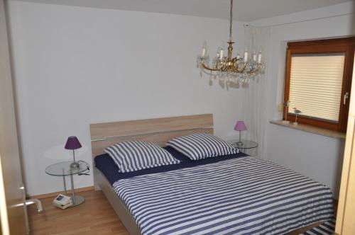 a bedroom with a bed with two pillows and a chandelier at Ferienwohnung Fischer in Frickingen