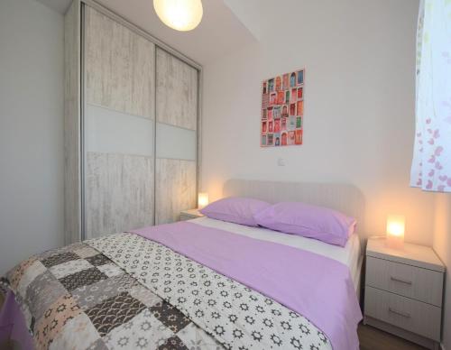 una camera da letto con un grande letto con lenzuola viola di Apartments Medna a Čižići