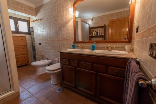 a bathroom with two sinks and a toilet and a mirror at Roque nublo rural houses I in Vega de San Mateo