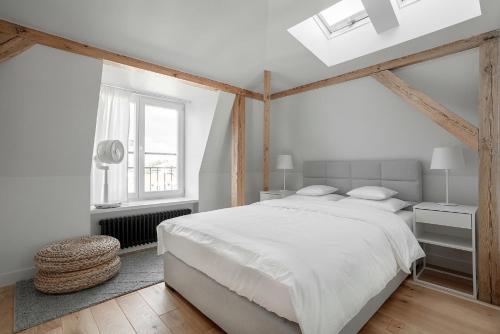 a white bedroom with a large bed and a window at VIU The Roof Apartment in Sopot