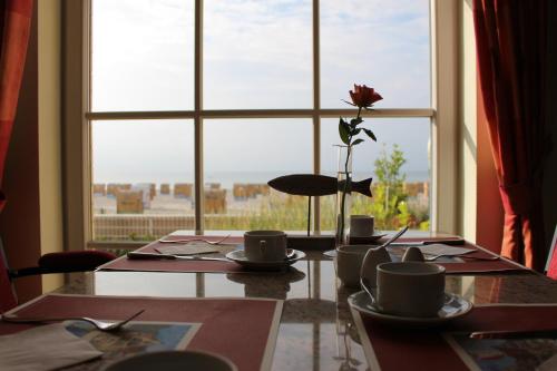 een tafel met bekers en een vaas met een bloem in een raam bij Strandhotel Grömitz in Grömitz