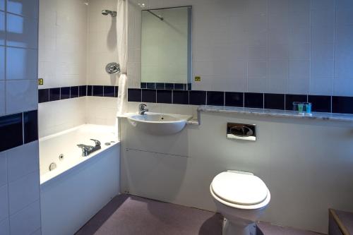 a bathroom with a toilet and a sink and a tub at The Savoy Hotel in Blackpool
