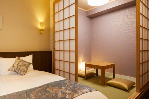 a room with a bed and a table and a mirror at Rinn Miyagawacho Grande in Kyoto
