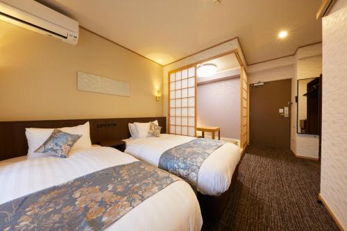 a hotel room with two beds and a television at Rinn Miyagawacho Grande in Kyoto