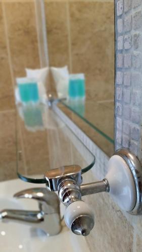 a bathroom sink with a faucet and a mirror at Miltons Country Lodge in Langford