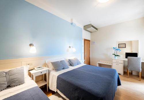 a hotel room with two beds and a desk at Hotel Andreaneri in Marina di Pietrasanta