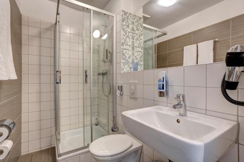 a bathroom with a sink and a shower and a toilet at MEININGER Hotel Hamburg City Center in Hamburg