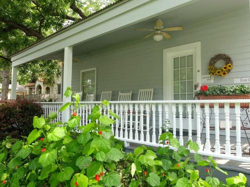 a house with a white fence and a porch with flowers at Comal Inn in New Braunfels