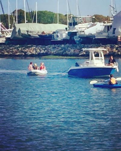 a group of people in boats in the water at Harbor View Landing in Mystic