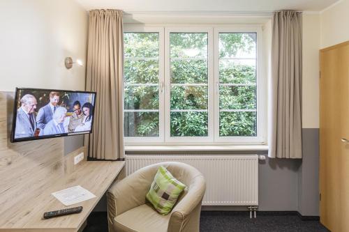 a living room with a tv and a chair and a window at Gästehaus Alexandra in Cuxhaven