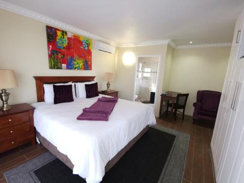 a bedroom with a large white bed with purple pillows at Lucolo Palace B&B - Mthatha in Mthatha