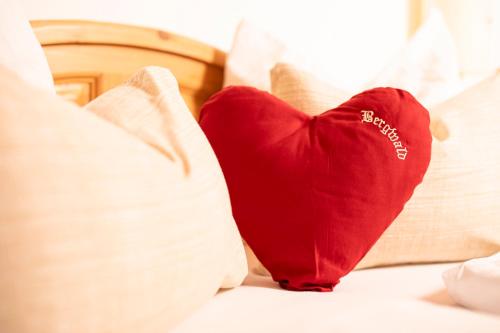 a red heart pillow sitting on a bed at Bergwald Appartements Alpbach in Alpbach