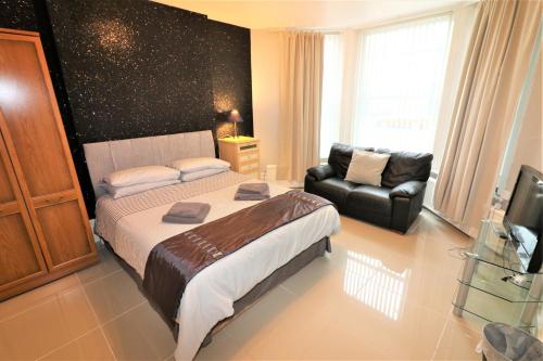 - une chambre avec un grand lit et un canapé dans l'établissement Marley Mansion Apartments - Borough, à Birkenhead