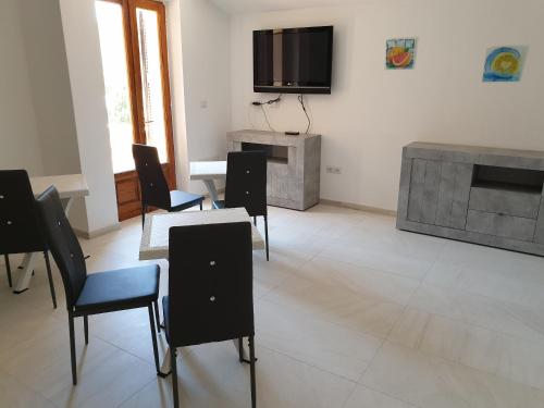 a living room with chairs and a table and a tv at Guest House Tra Rocce E Mare in La Maddalena