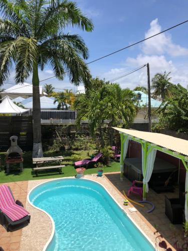 una piscina en un patio trasero con palmeras en Location tropical, en Sainte-Anne