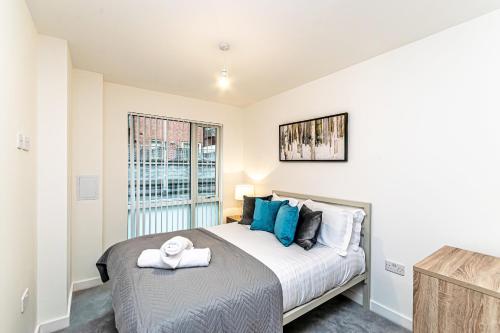 a bedroom with a large bed with blue pillows at Halo House Apartments in Manchester