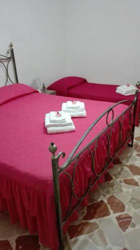 a bed with pink sheets and white towels on it at A casa di Gio’ in Marsala