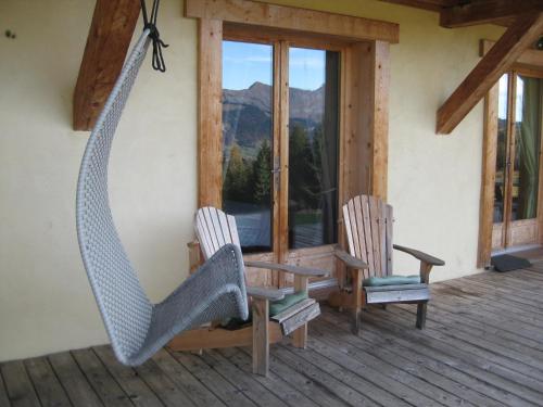 two chairs and a hammock on a porch at La Ferme des Georgières "Séjour en tout compris" in Notre-Dame-de-Bellecombe