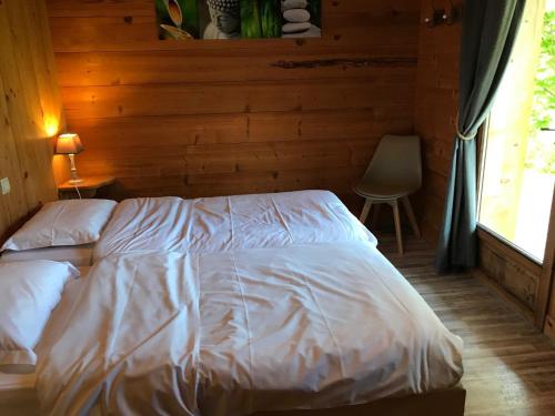 a bed in a bedroom with a wooden wall at La Ferme des Georgières "Séjour en tout compris" in Notre-Dame-de-Bellecombe