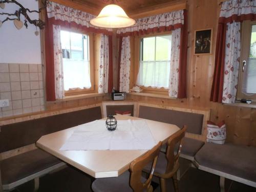 a dining room with a table and chairs and windows at Haus zur Kapelle in Sankt Gallenkirch