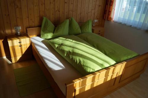 un letto in legno con lenzuola e cuscini verdi di Schöllhorn Judith a Sankt Gallenkirch
