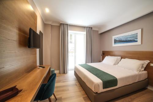 Pokój hotelowy z łóżkiem, biurkiem i telewizorem w obiekcie Toledo Relais Exclusive Rooms - By Pera Rooms Collection w mieście Neapol