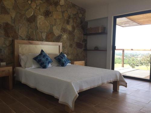 um quarto com uma cama com almofadas azuis em Chalet Nativo - Fabulous Terrace & Vineyard em Valle de Guadalupe